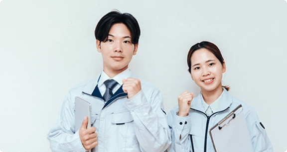作業着を着た男女2名が拳を握りしめています